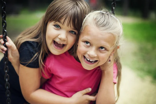 Niñas felices balanceándose en un parque — Foto de Stock