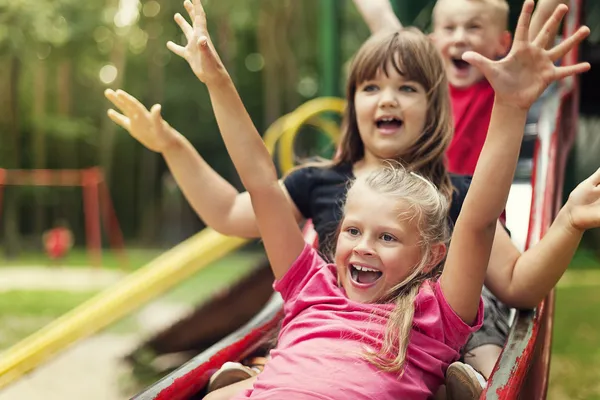 Happy kids playing on slide — Stock Photo, Image