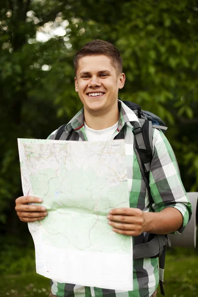 Homem segurando um mapa na floresta — Fotografia de Stock