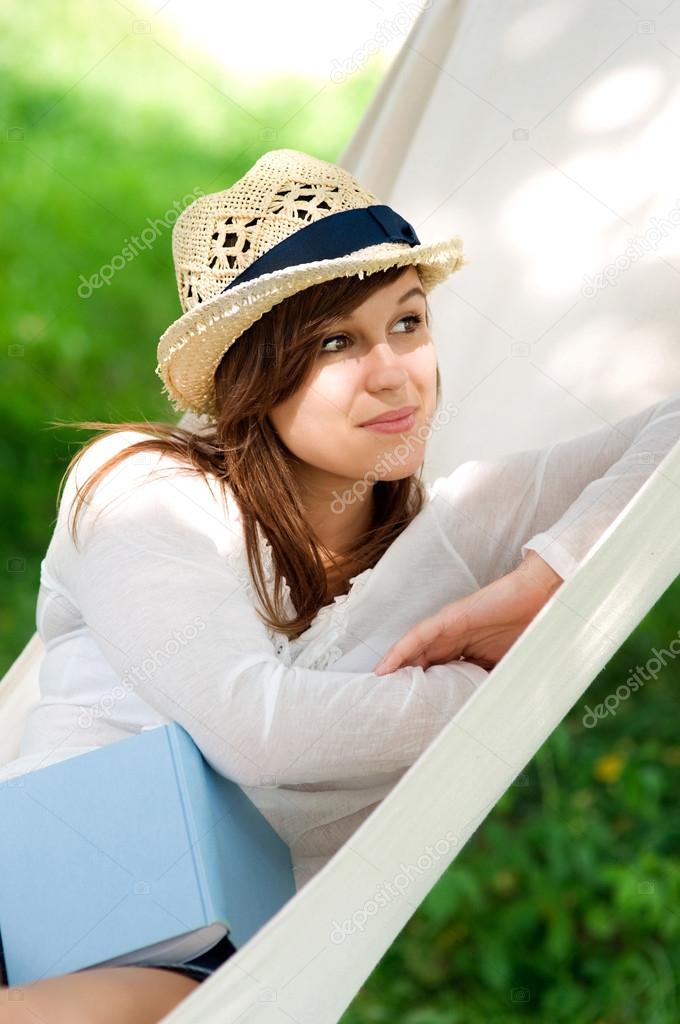 Woman relaxing in a hammock with book