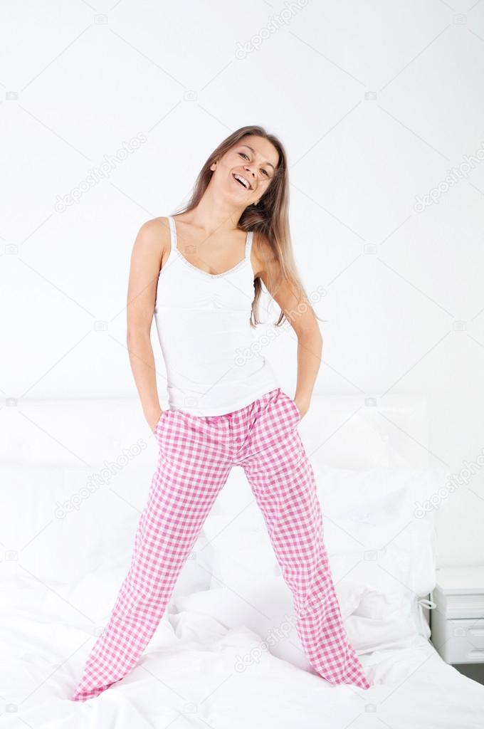 Young woman jumping on bed