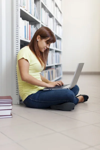 Estudante usando laptop em bibliotecário — Fotografia de Stock