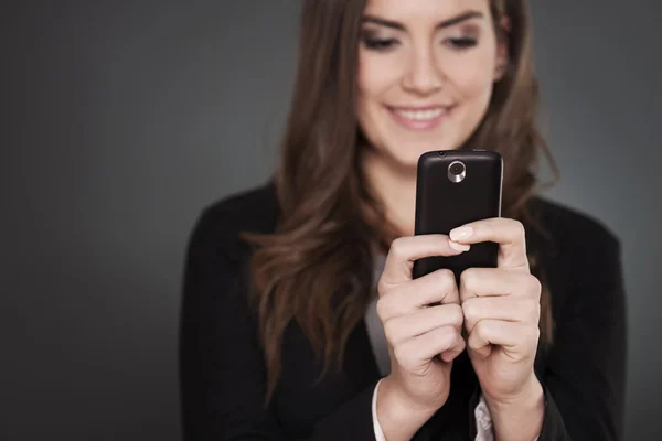 Fröhliche Geschäftsfrau, die auf dem Handy SMS schreibt — Stockfoto