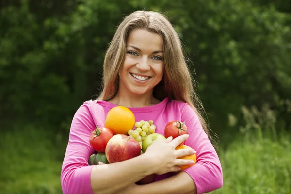 Mujer joven sosteniendo frutas y verduras — Foto de Stock