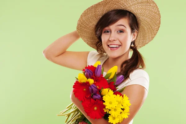 Mulher morena sorridente com chapéu e flor de primavera — Fotografia de Stock