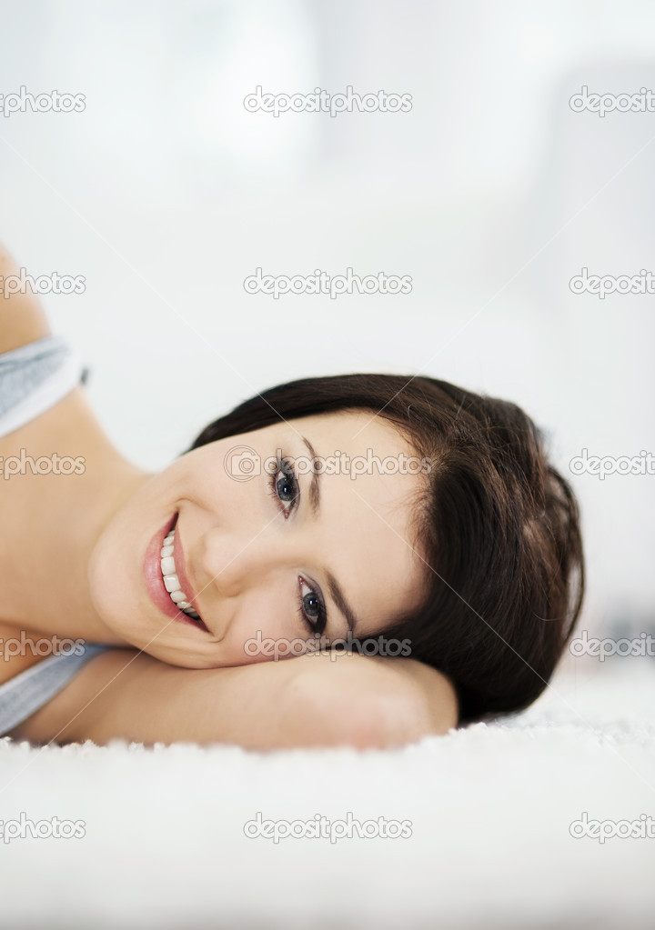 Attractive and smiling woman lying on the carpet