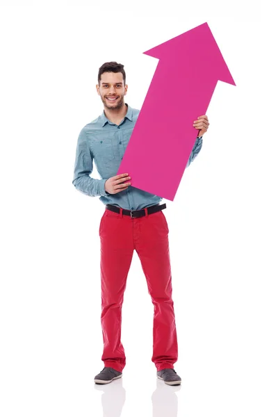 Uomo sorridente che tiene il segno rosa della freccia — Foto Stock