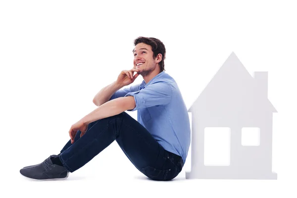 Dreaming man sitting next to a sign home — Stock Photo, Image