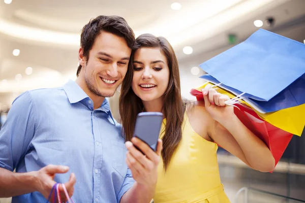 Sorrindo casal verificando algo no telefone celular — Fotografia de Stock