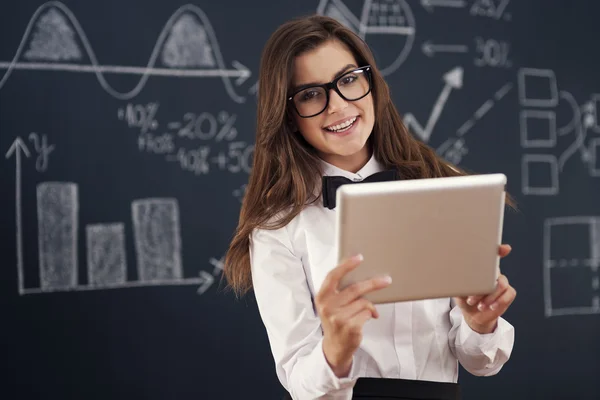 Smiling teacher using digital tablet in classroom