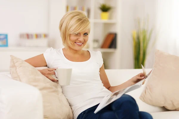 Mulher loira relaxando em casa com café e jornal — Fotografia de Stock