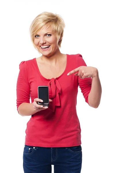 Lachende jonge vrouw wijzend op scherm van mobiele telefoon — Stockfoto