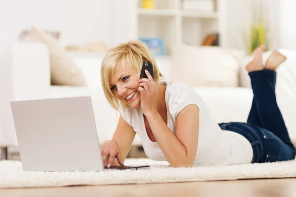 Mujer feliz usando el ordenador portátil y hablando en el teléfono móvil —  Fotos de Stock