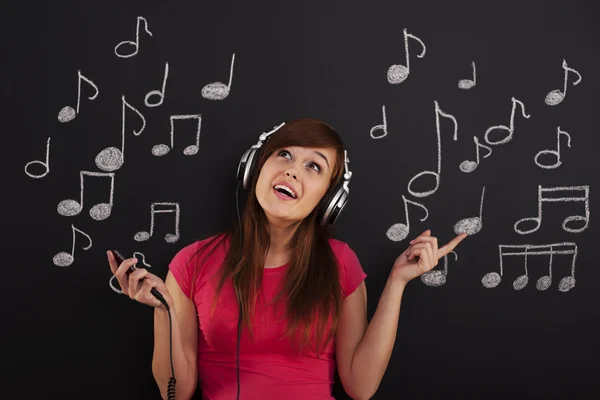 Mulher feliz ouvindo música através de fones de ouvido — Fotografia de Stock