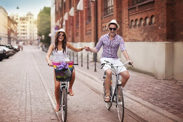 Glada unga par hålla händer och ridning på cykel — Stockfoto