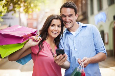 mutlu çift alışveriş sırasında akıllı telefon kullanma