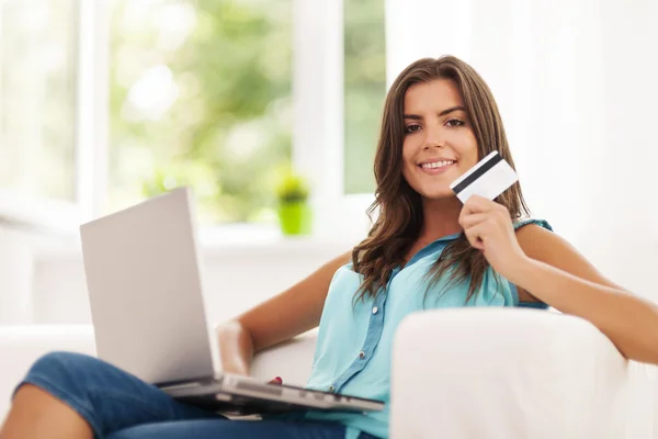 Mulher sorrindo usando laptop e segurando cartão de crédito — Fotografia de Stock