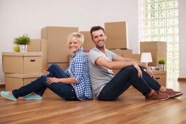 Couple sitting back to back in their new home clipart