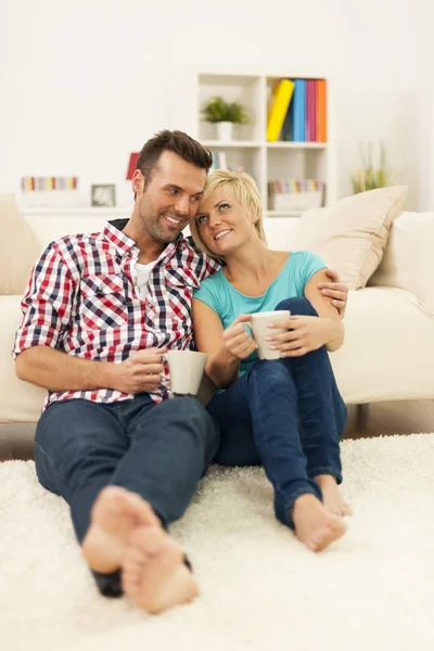 Happy couple sitting on the floor and drinking coffee — Stock Photo, Image