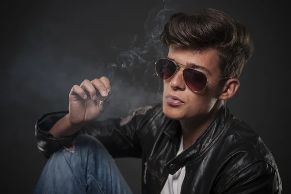 Portrait of young man wearing sunglasses and smoking — Stock Photo, Image