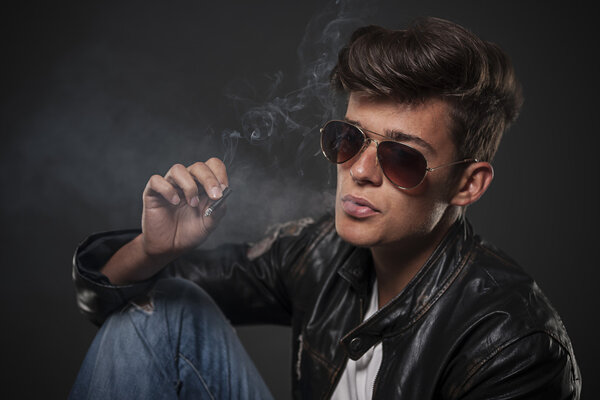 Портрет молодого человека в солнцезащитных очках и курении
