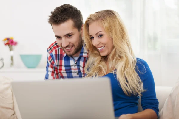 Coppia sorridente utilizzando il computer portatile a casa — Foto Stock