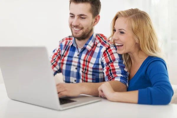 Ridere coppia utilizzando il computer a casa — Foto Stock