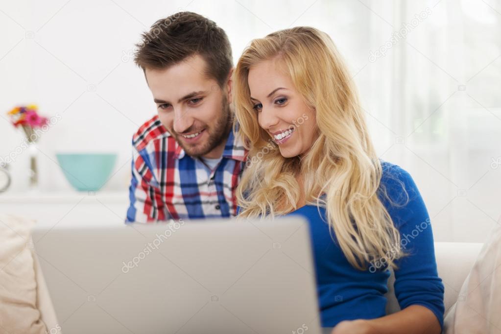 Smiling couple using laptop at home