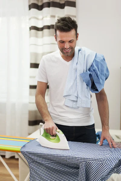Un homme souriant repasse ses chemises — Photo