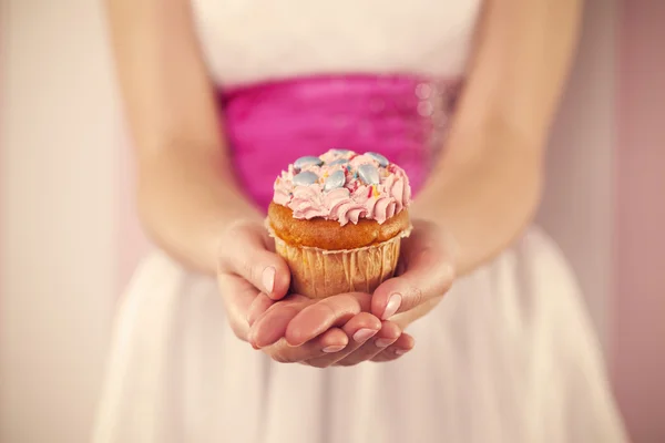 Kobieta gospodarstwa różowy muffin — Zdjęcie stockowe