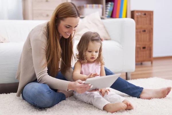 デジタル タブレットで彼女の娘を助ける母 — ストック写真