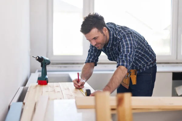 Carpintero que mide tablones de madera — Foto de Stock