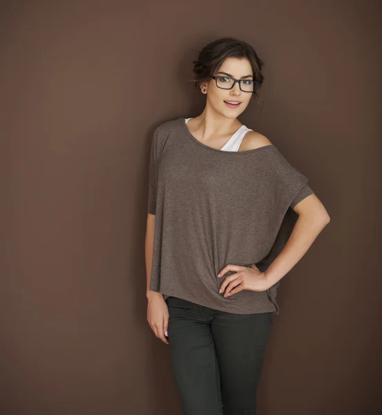 Woman in glasses posing on brown wall — Stock Photo, Image