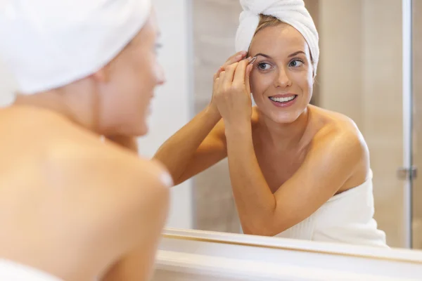 Woman tweezing eyebrows — Stock Photo, Image