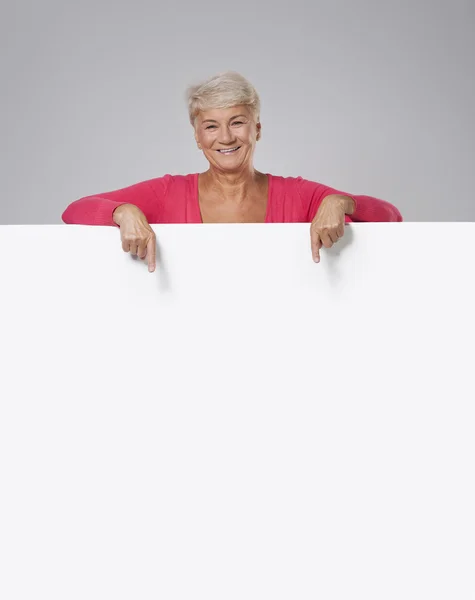 Senior woman showing on empty whiteboard — Stock Photo, Image