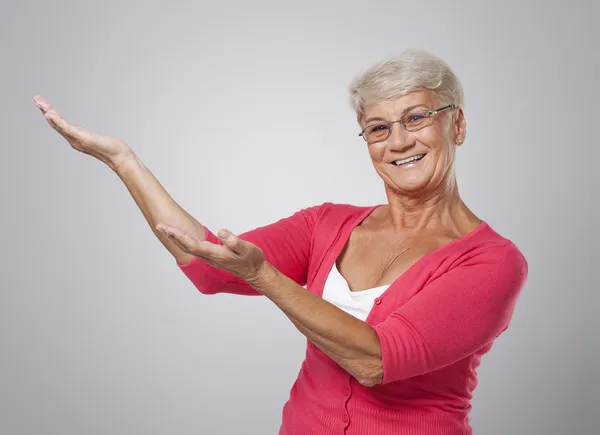 Senior vrouw tonen op kopie ruimte — Stockfoto