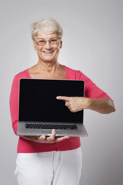 Mujer mayor mostrando en el ordenador portátil — Foto de Stock