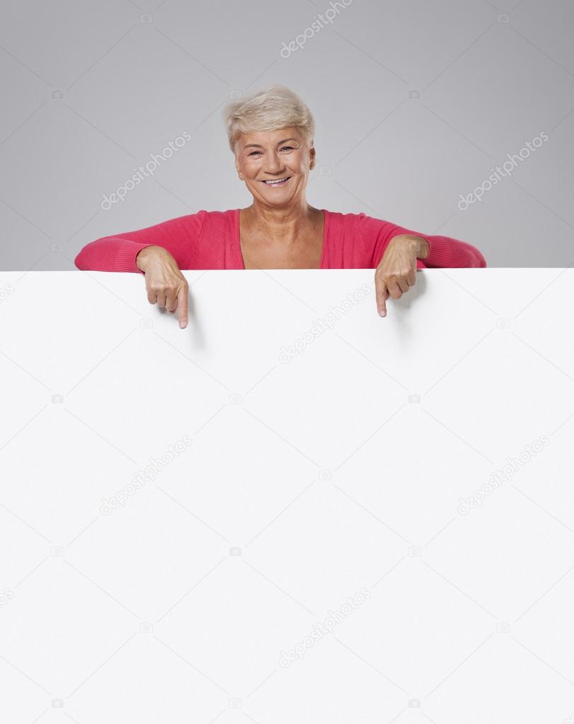 Senior woman showing on empty whiteboard