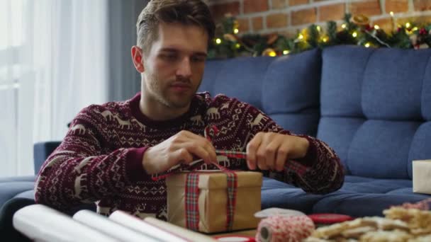 Молодой Мужчина Упаковывает Рождественские Подарки Съемка Красной Гелиевой Камерой — стоковое видео