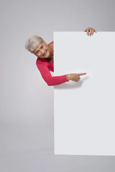 Senior woman showing on empty whiteboar — Stock Photo, Image