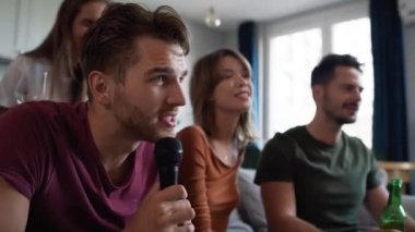 Genç yetişkin arkadaşlar evde karaoke yapıyorlar. 8K 'da kırmızı helyum kamerayla çekildi. 