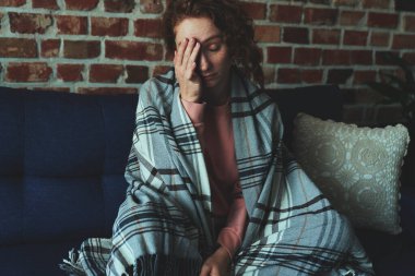 Depresyondaki genç beyaz kadın kanepenin yanında yerde sessizce yatıyor.