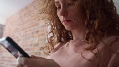 Yakın çekim ve düşük açılı videoda cep telefonu kullanan endişeli beyaz bir kadın görülüyor. 8K 'da kırmızı helyum kamerayla çekildi..