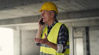 Kafkasyalı kıdemli mühendis inşaat alanında telefonla konuşuyor. 8K 'da kırmızı helyum kamerayla çekildi.     
