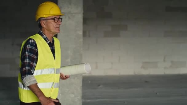 Engenheiro Sênior Caucasiano Caminhando Segurando Planos Canteiro Obras Tiro Com — Vídeo de Stock