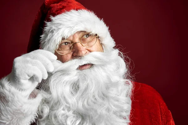 Uśmiechnięty Biały Mikołaj Dotykający Wąsów Czerwonym Tle — Zdjęcie stockowe