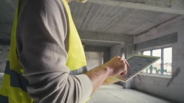 Kafkas mühendisinin dijital tablet üzerindeki inşaat projesinin düşük açılı görüntüleri. 8K 'da kırmızı helyum kamerayla çekildi.  