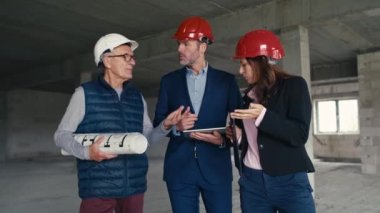 Bir grup beyaz mühendis ve yatırımcı inşaat alanında yürüyor ve tartışıyorlar. 8K 'da kırmızı helyum kamerayla çekildi.      