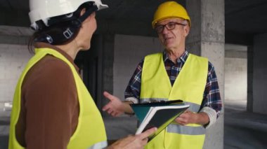 Erkek ve beyaz kadın mühendisler inşaat alanında konuşuyorlar. 8K 'da kırmızı helyum kamerayla çekildi.   