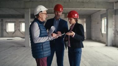 Kafkasyalı mühendis ve yatırımcı grubunun inşaat alanında ayakta durup tartışmalarını gösteren statik geniş çekim görüntüleri. 8K 'da kırmızı helyum kamerayla çekildi.   
